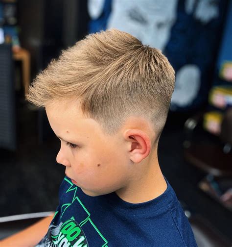 The suave bald fade with a high top is a trendy, versatile haircut option for teen boys. This style features a carefully blended fade on the sides. It creates a smooth transition from short to longer hair on top. The high top adds height and visual interest. It gives the overall look a stylish and contemporary touch.